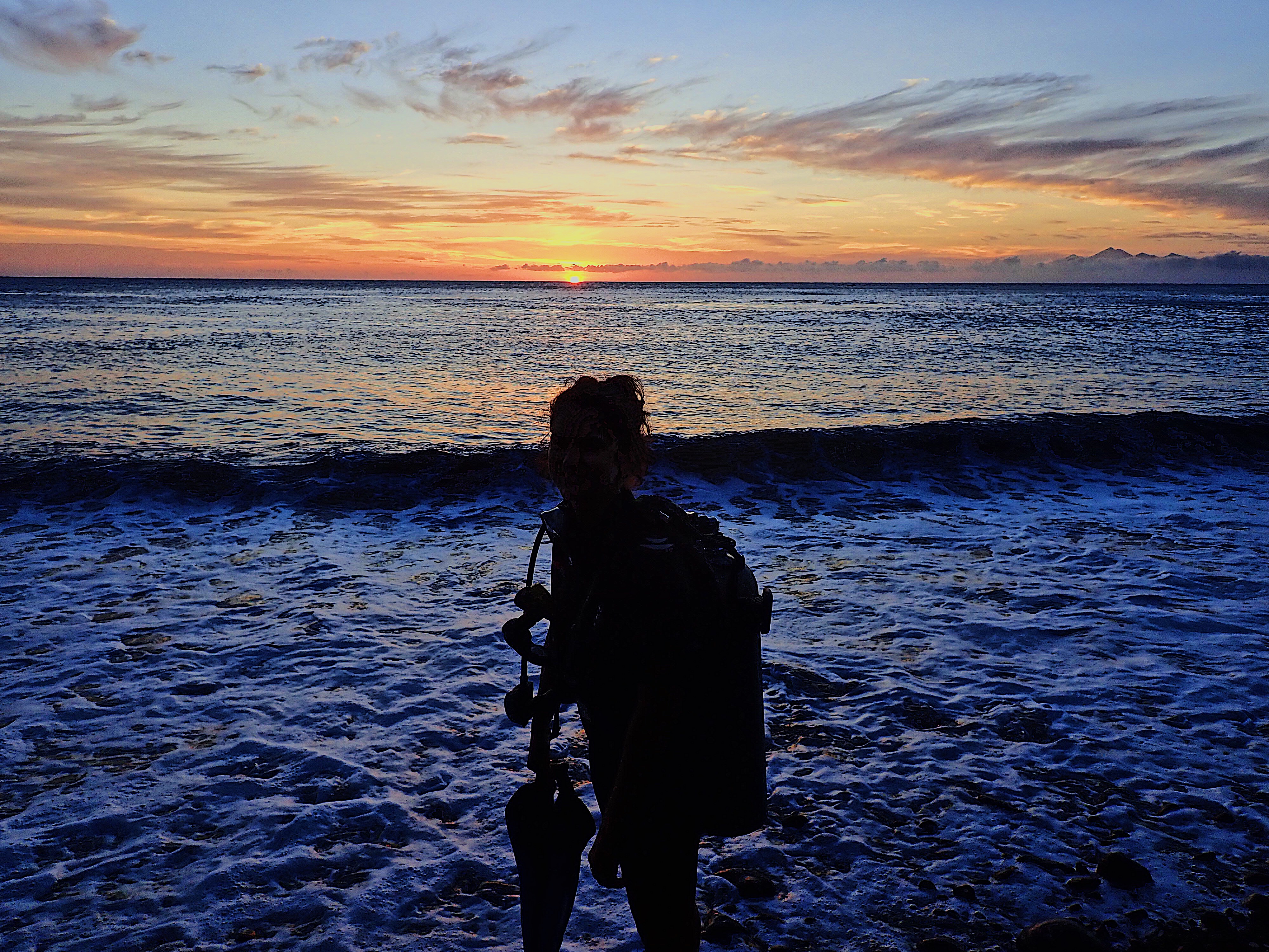 Scuba diver entering the water at sunrise time on the USAT Liberty wreck in Tulamben