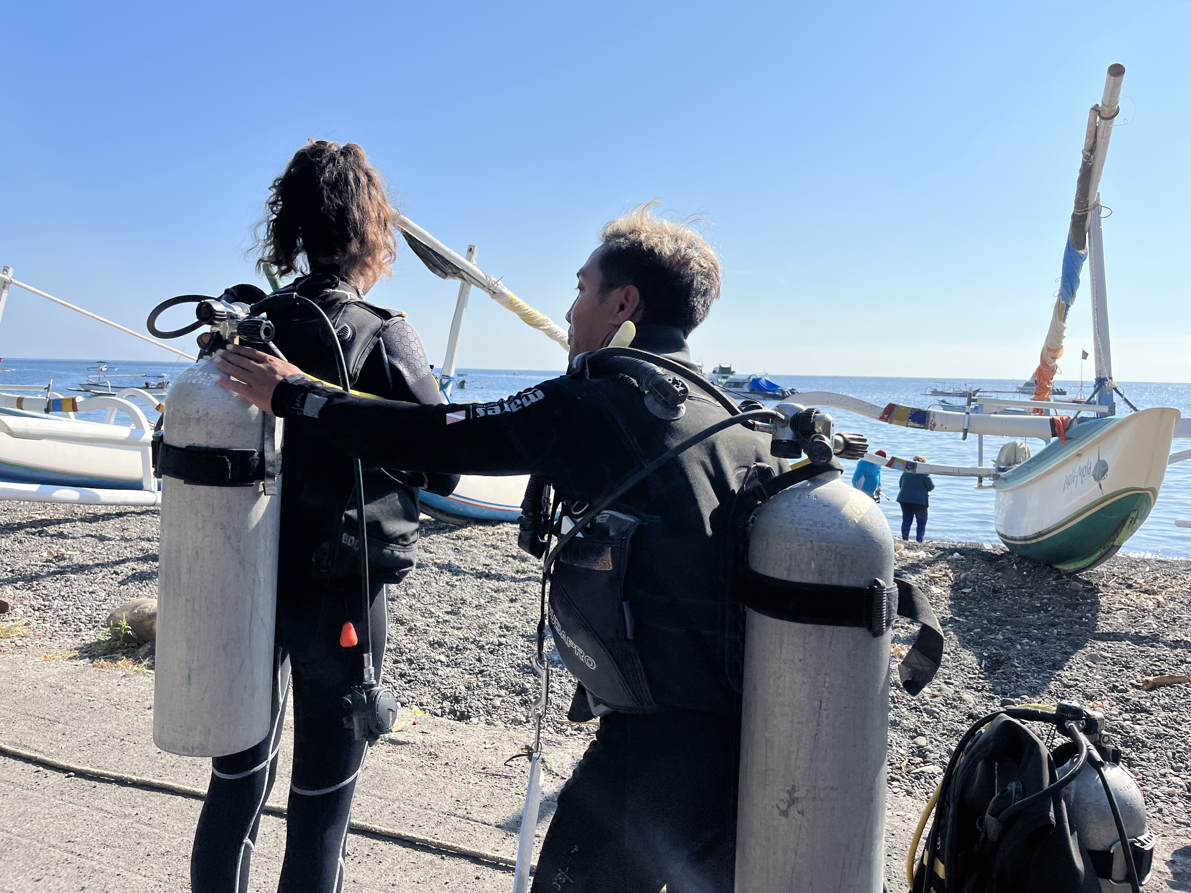 Instructor Gede and student Eloise checking their Air as part of the BWRAF buddy check of the PADI Open Water diver course in Amed, Bali