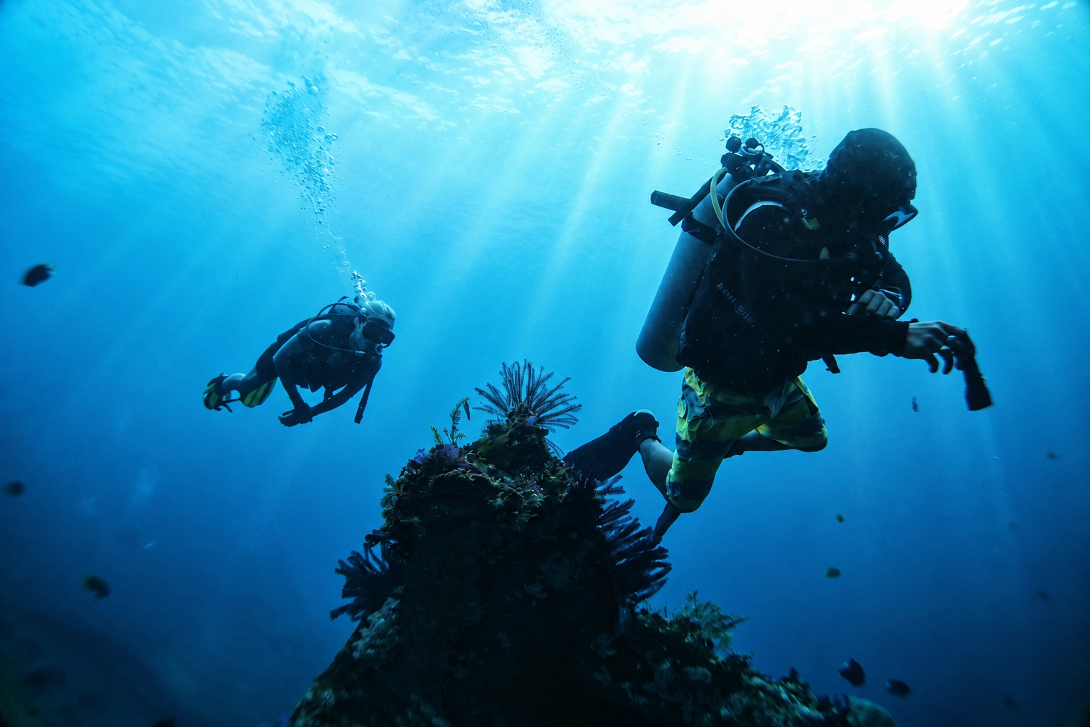 Scuba divers on the USAT Liberty wreck with morning light rays in Tulamben, Bali